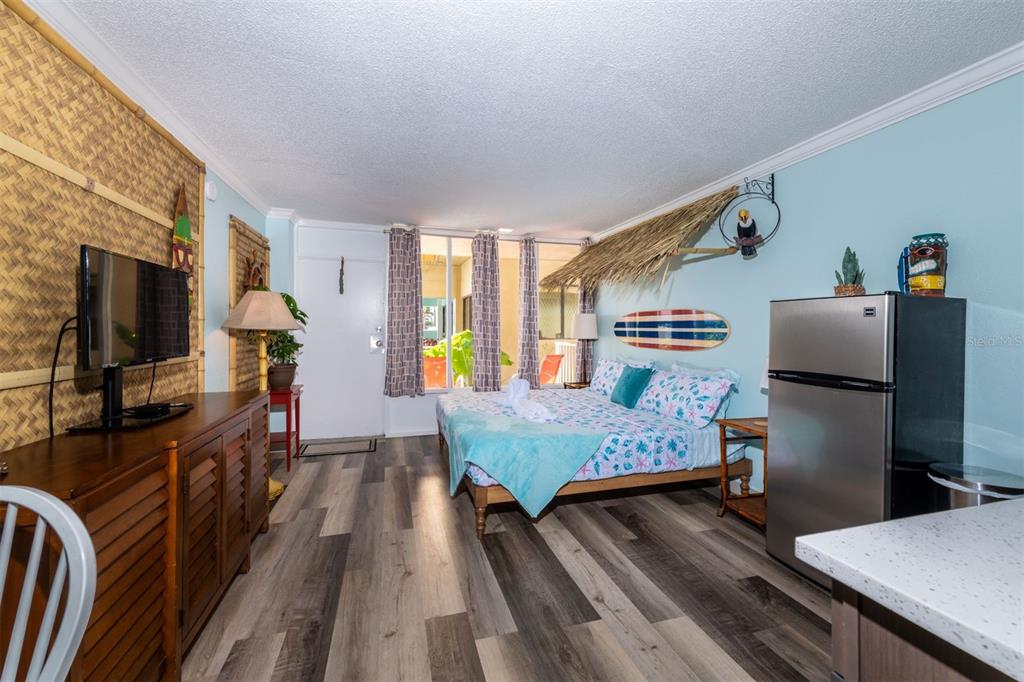 A bedroom with a surfboard wall decoration, a thatched canopy, and a stainless steel refrigerator — 2043 S ATLANTIC AVENUE UNIT 105, DAYTONA BEACH SHORES, FL