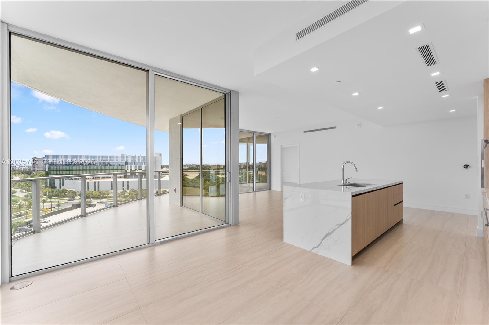 A modern kitchen island with marble countertops sits in an open living space with balconies — 2411 Laguna Circle # 705, North Miami FL 33181, NORTH MIAMI, FL