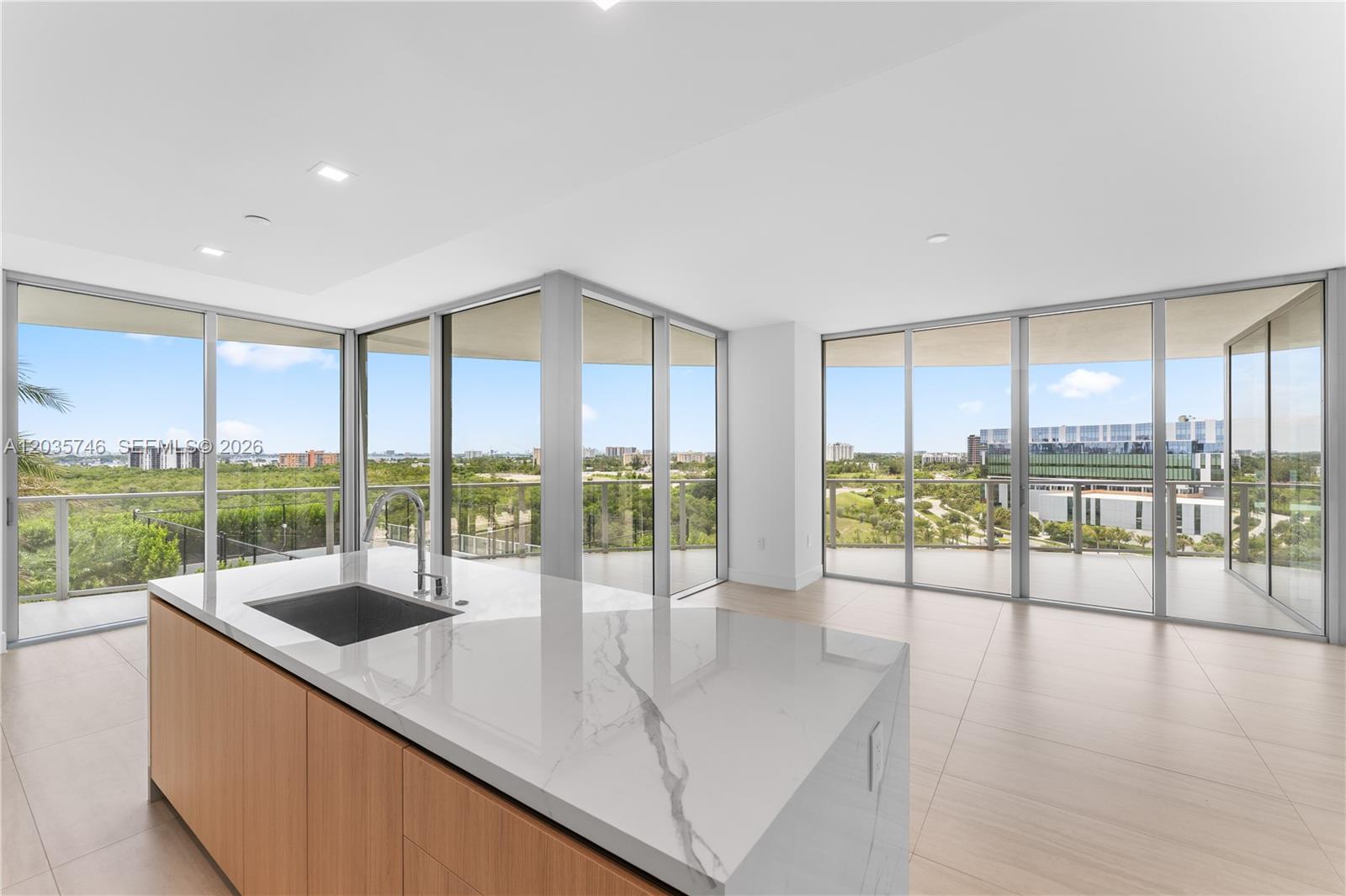 A modern kitchen island with a marble countertop sits in a room with floor-to-ceiling windows — 2411 Laguna Circle # 705, North Miami FL 33181, NORTH MIAMI, FL