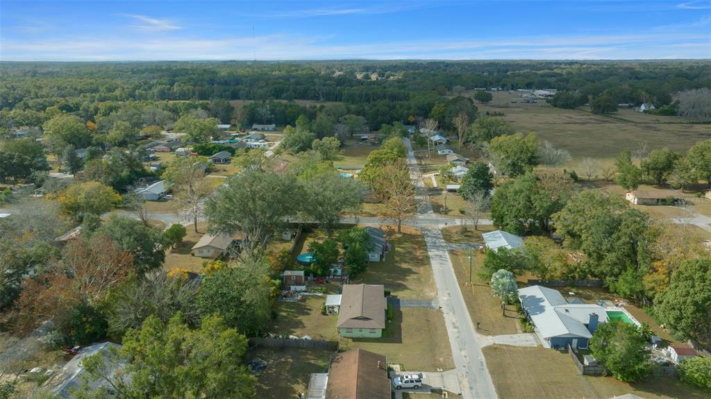 An aerial view shows a residential neighborhood with houses, trees, and roads under a blue sky — 2004 NE 52ND STREET, OCALA, FL