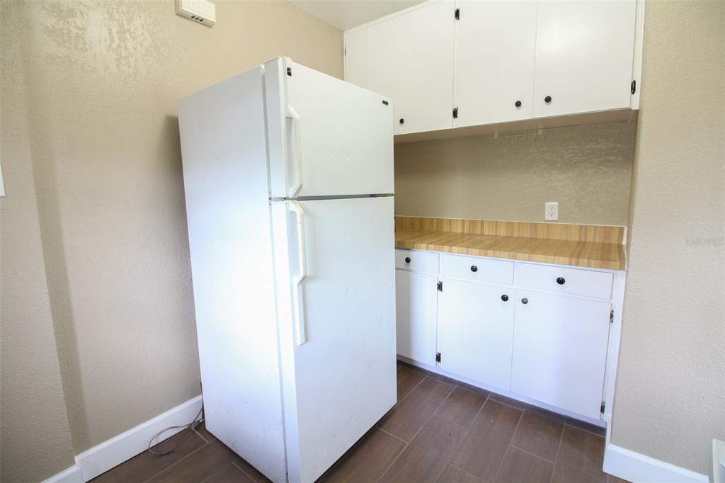 A kitchen features a white refrigerator, white cabinets, and a wood-patterned countertop — 1114 S TENNESSEE AVENUE, LAKELAND, FL