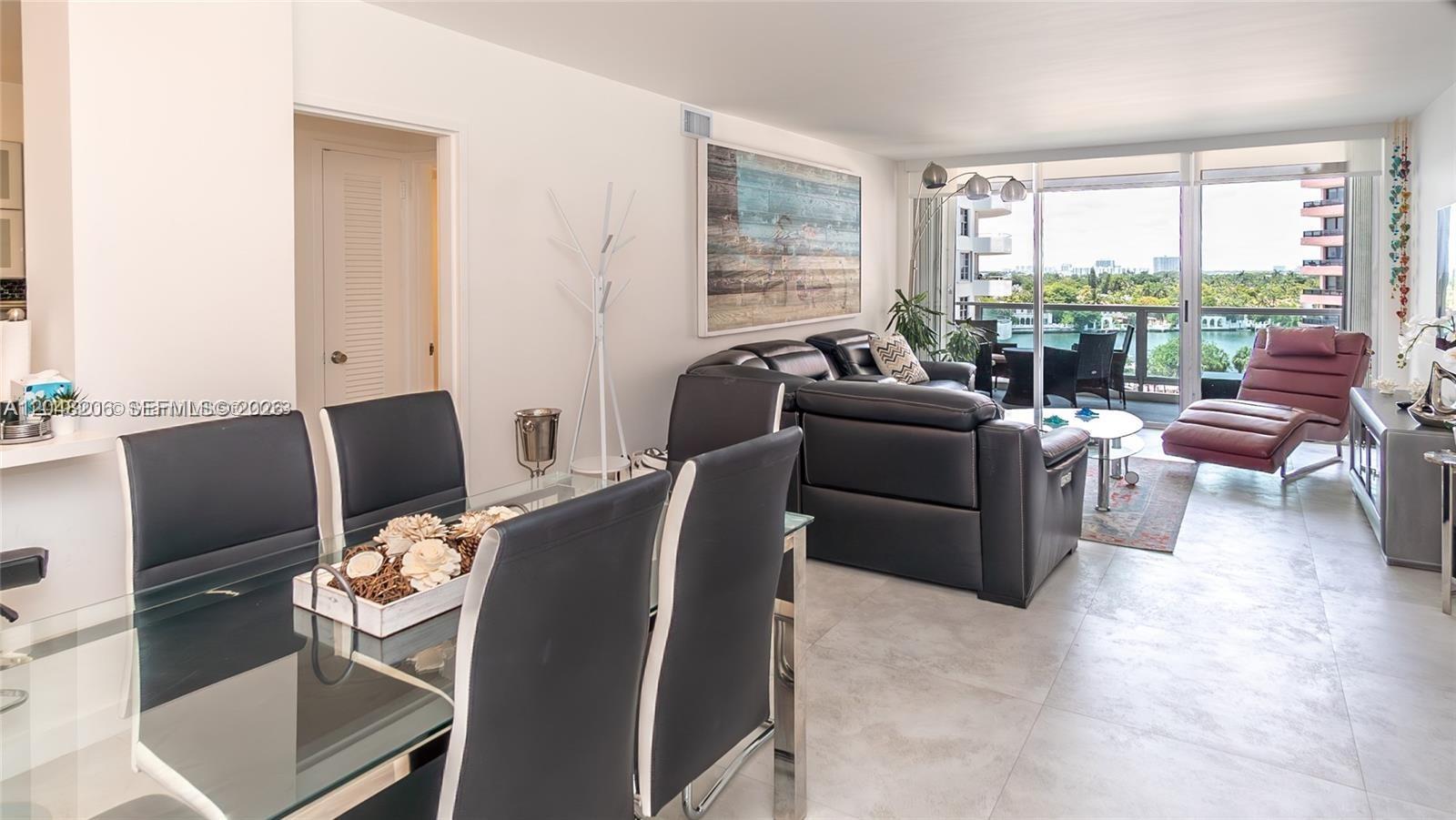 A dining area and living room with tile floors open to a balcony with water views — 5161 Collins Ave # 811, Miami Beach FL 33140, MIAMI BEACH, FL