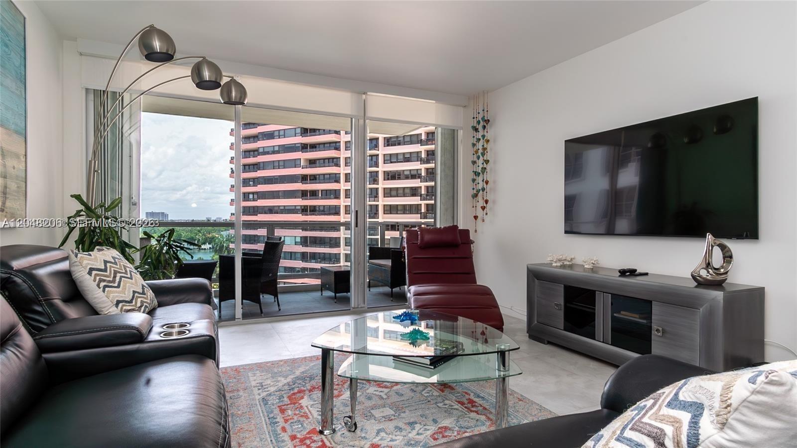 A living room features a leather sofa, glass coffee table, and balcony with city views — 5161 Collins Ave # 811, Miami Beach FL 33140, MIAMI BEACH, FL