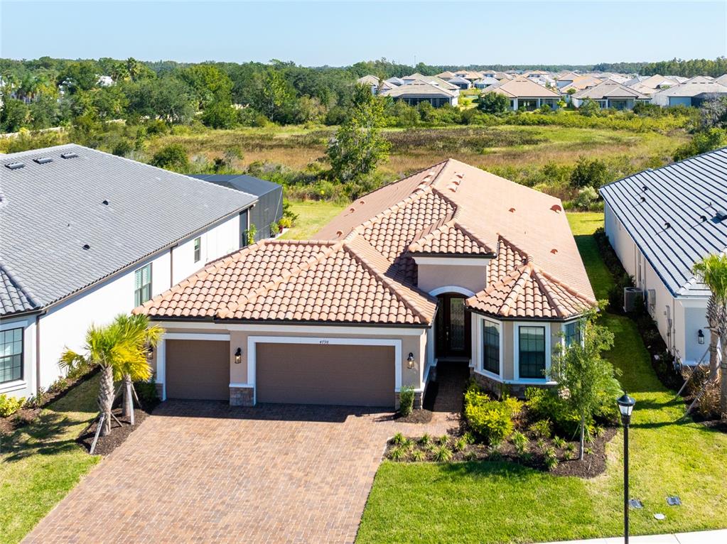 An aerial view of a single-story house with a tile roof and a paved driveway — 4798 ROSATTI ROAD, WESLEY CHAPEL, FL