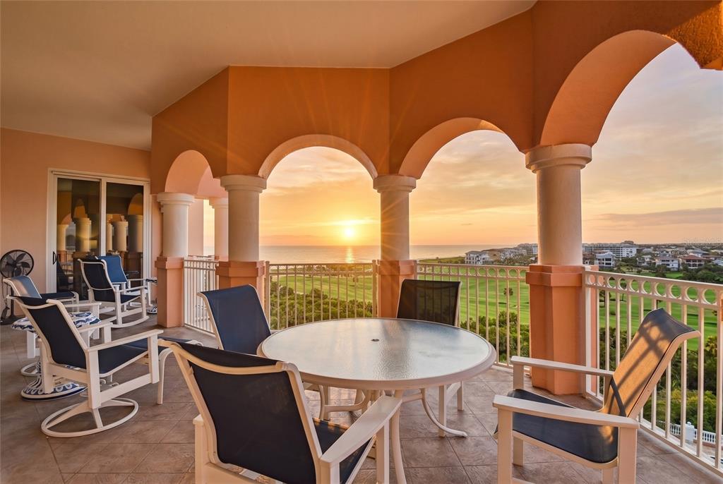 A covered balcony with arched columns overlooks a golf course and the ocean at sunset — 200 OCEAN CREST DRIVE UNIT 642, PALM COAST, FL