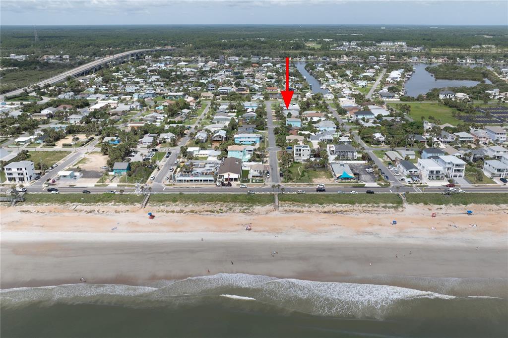 An aerial view shows a beach town with a red arrow pointing to a house — 308 N 6TH STREET, FLAGLER BEACH, FL