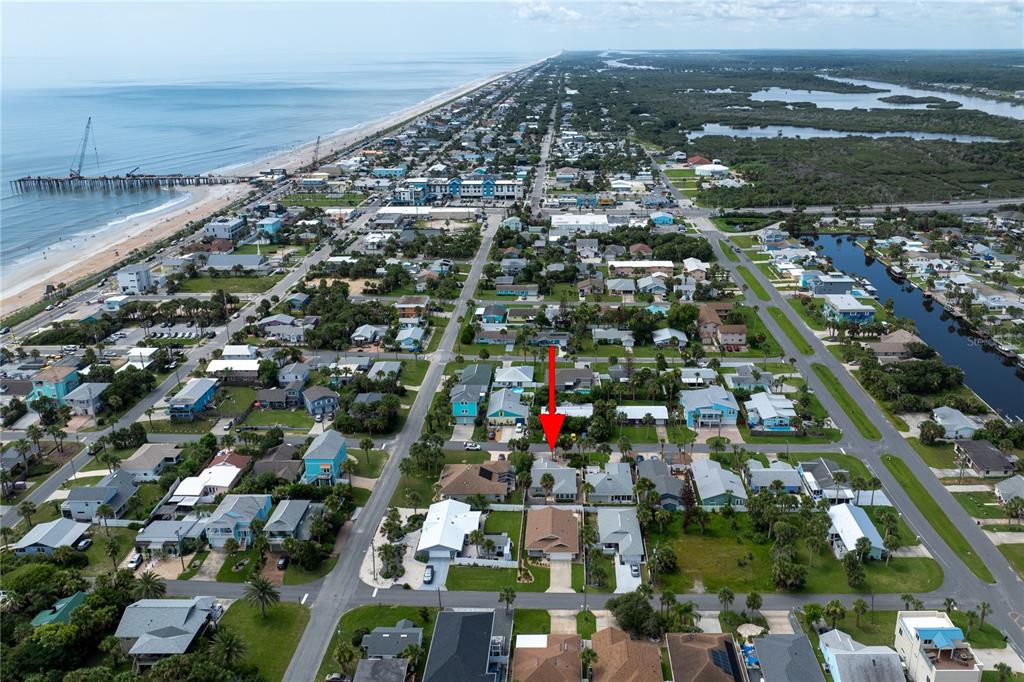 An aerial view shows a coastal neighborhood with a red arrow pointing to a house — 308 N 6TH STREET, FLAGLER BEACH, FL
