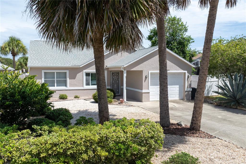 A single-story house with a beige exterior, a gravel front yard, and palm trees — 308 N 6TH STREET, FLAGLER BEACH, FL