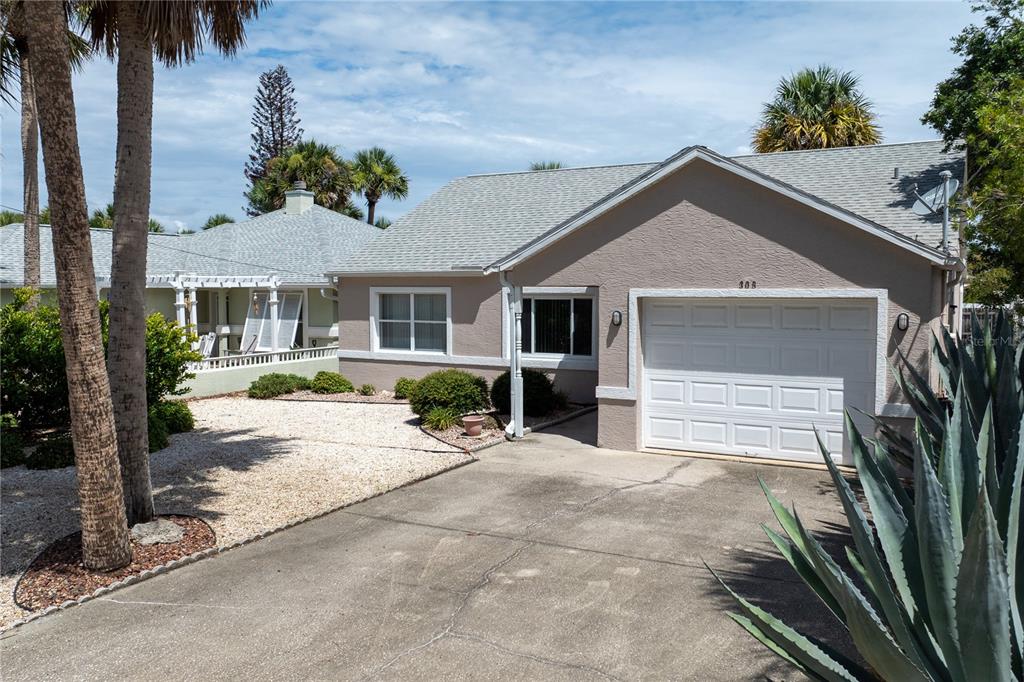 A single-story house with a beige stucco exterior, a white garage door, and a gravel yard — 308 N 6TH STREET, FLAGLER BEACH, FL
