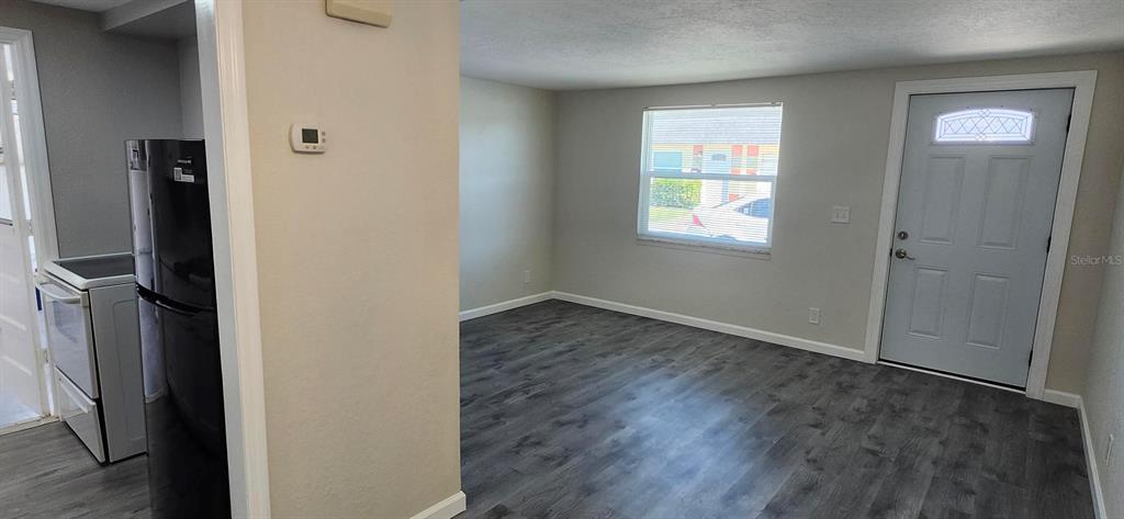 A kitchen with a black refrigerator and stove opens into a living area with gray flooring — 5000 BITNER STREET, NEW PORT RICHEY, FL
