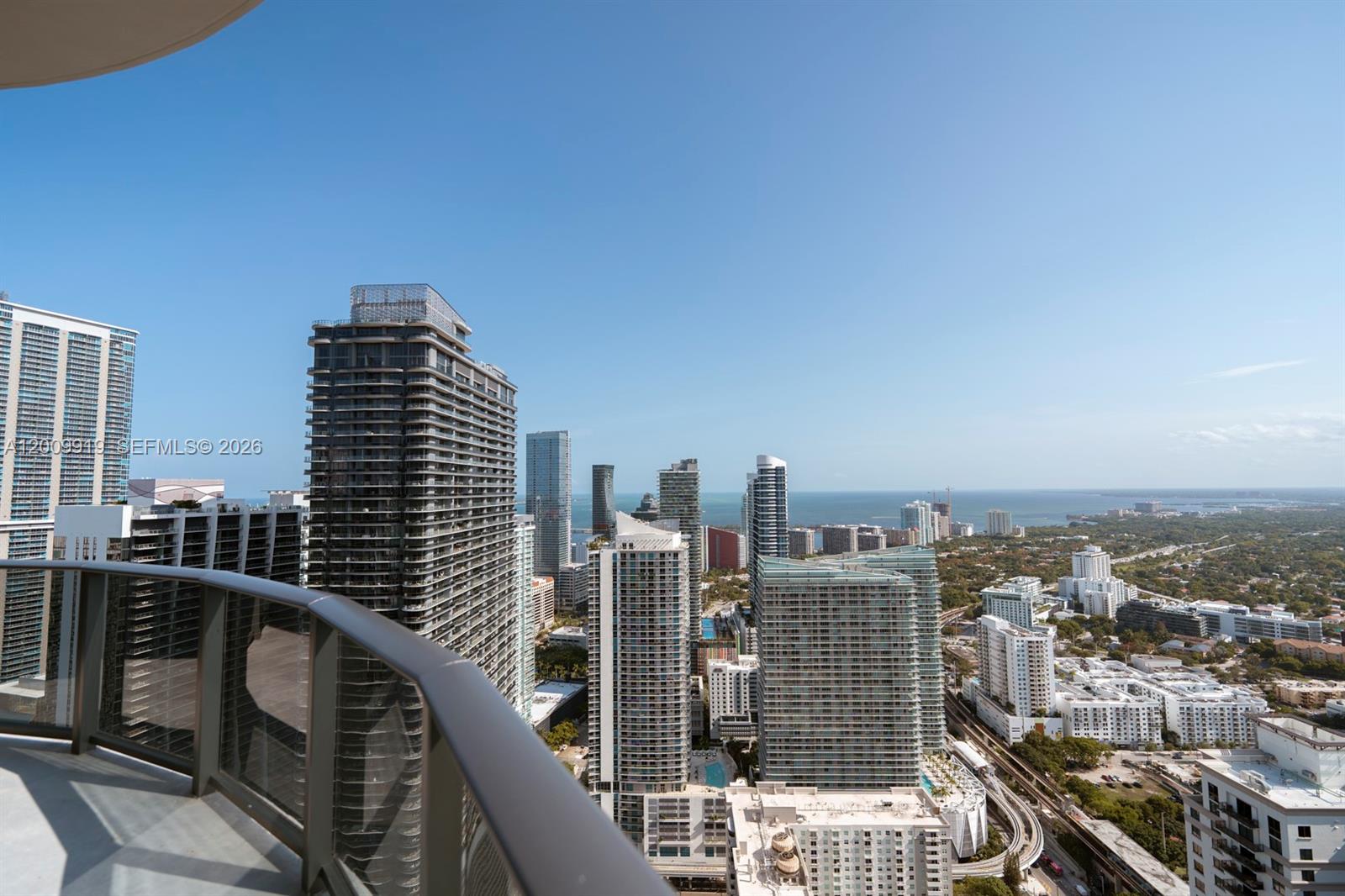 A high-angle view from a balcony overlooking a dense city skyline and the ocean — 45 SW 9th St # 4906, Miami FL 33130, MIAMI, FL