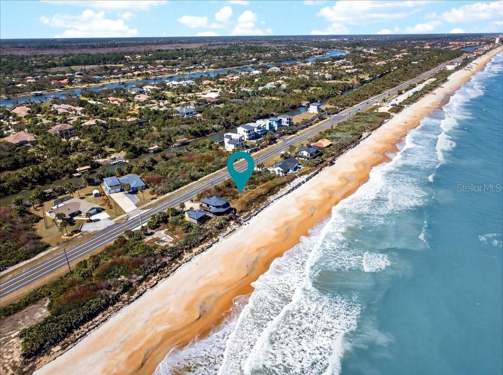 An aerial view shows a coastal house located between a road and the ocean — 3527 N OCEAN SHORE BOULEVARD, PALM COAST, FL