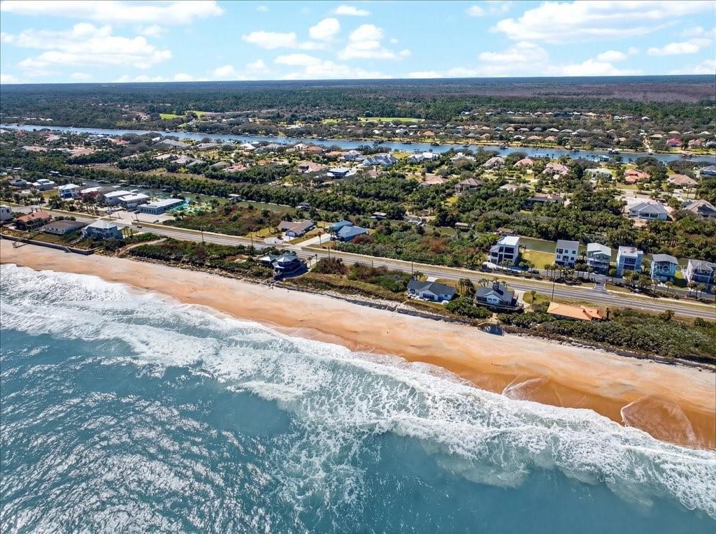 An aerial view of a sandy beach, a coastal road, and residential homes near water — 3527 N OCEAN SHORE BOULEVARD, PALM COAST, FL