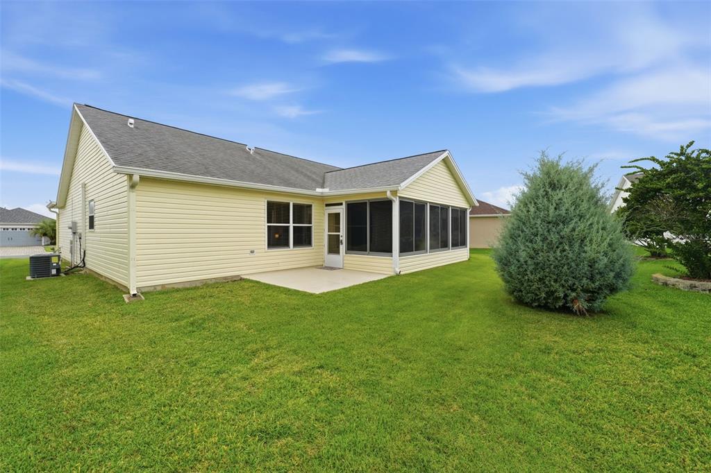 The exterior of a yellow-sided house features a screened-in porch and a concrete patio — 17173 SE 79TH MCLAWREN TERRACE, THE VILLAGES, FL