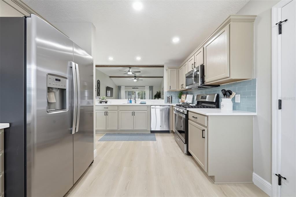 A kitchen with light gray cabinets, stainless steel appliances, and a light blue tile backsplash — 17173 SE 79TH MCLAWREN TERRACE, THE VILLAGES, FL