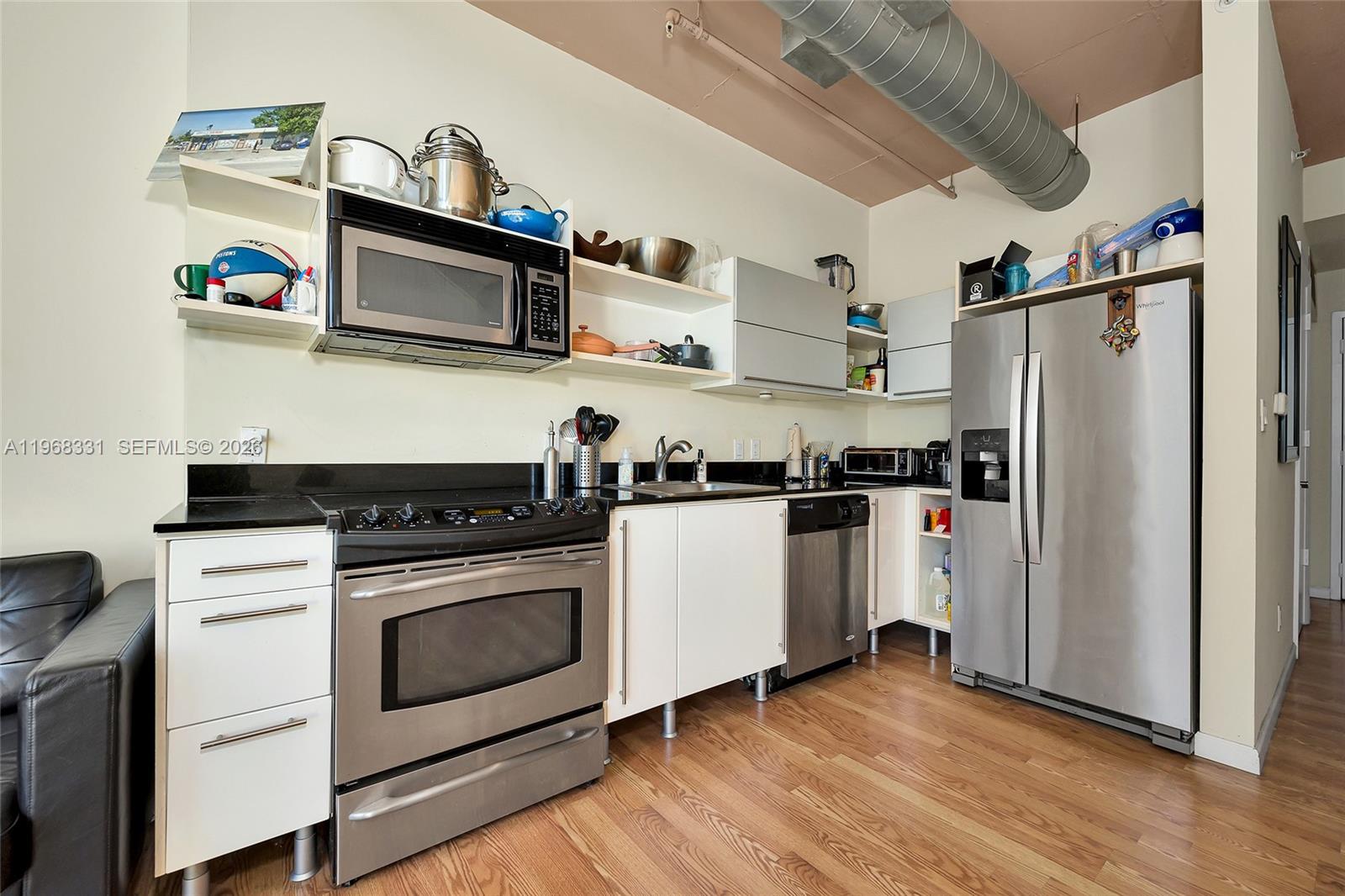 A kitchen features stainless steel appliances, white cabinets, black countertops, and an exposed ceiling duct — 690 SW 1st Ct # 1504, Miami FL 33130, MIAMI, FL