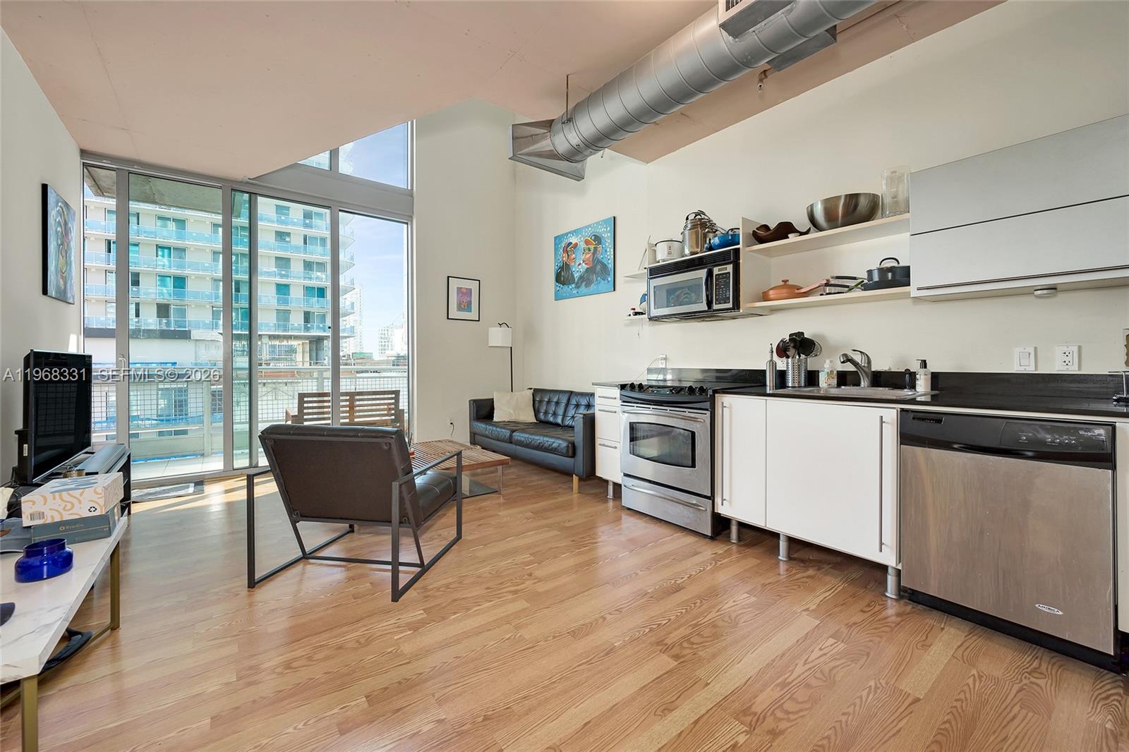 This studio apartment features an open kitchen, hardwood floors, and floor-to-ceiling windows — 690 SW 1st Ct # 1504, Miami FL 33130, MIAMI, FL