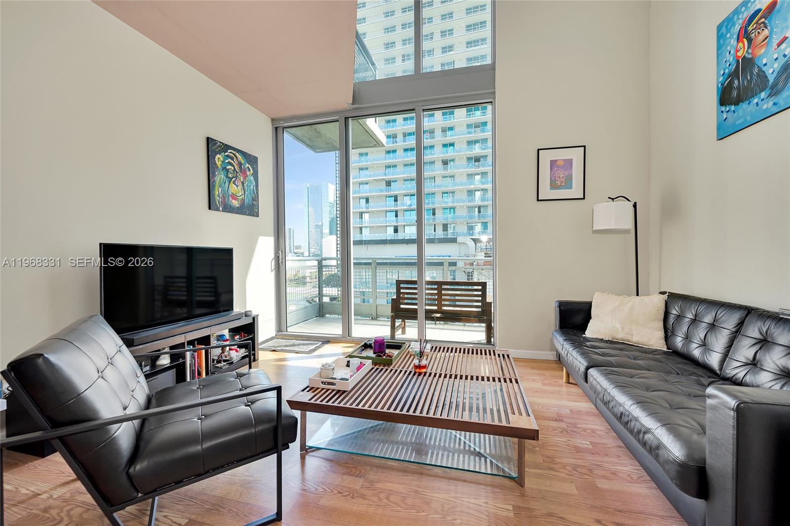 A living room features black leather furniture, a slatted coffee table, and floor-to-ceiling windows — 690 SW 1st Ct # 1504, Miami FL 33130, MIAMI, FL