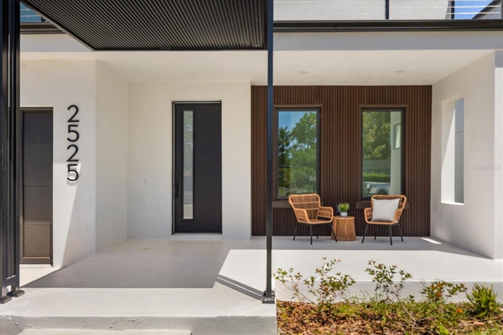 A modern home exterior features a white porch, dark wood paneling, and two wicker chairs — 2525 18TH AVENUE N, ST PETERSBURG, FL