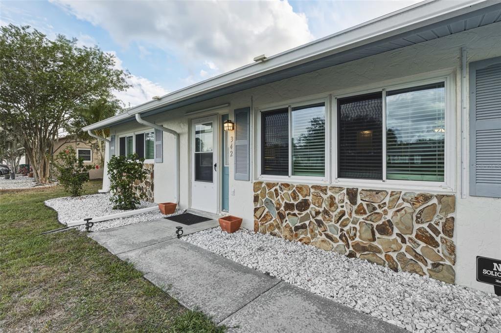 The exterior of a single-story house features white stucco walls, stone accents, and blue shutters — 342 AURORA STREET, PORT CHARLOTTE, FL