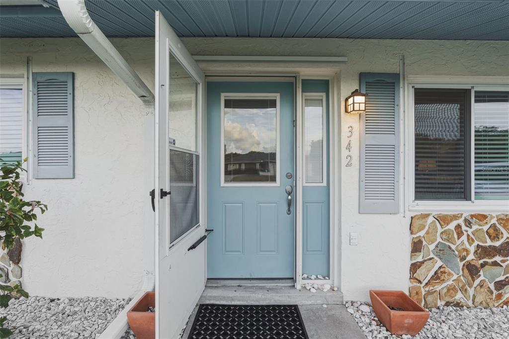 A light blue front door with a storm door and house number 342 — 342 AURORA STREET, PORT CHARLOTTE, FL