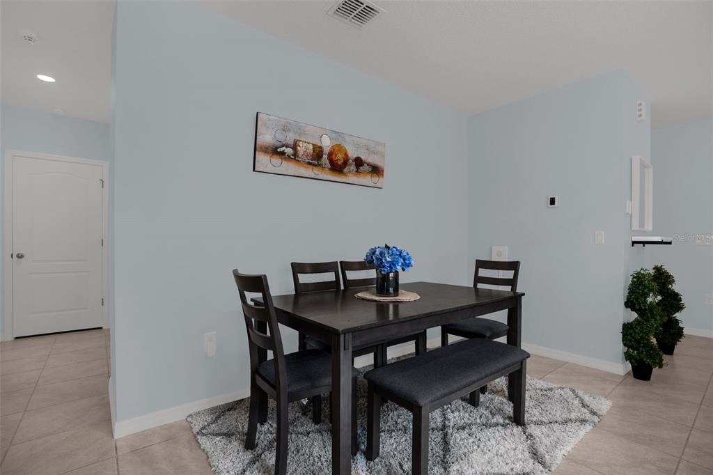 A dining area features a dark wood table with chairs and a bench on a rug — 334 CHARLES DRIVE, DELAND, FL