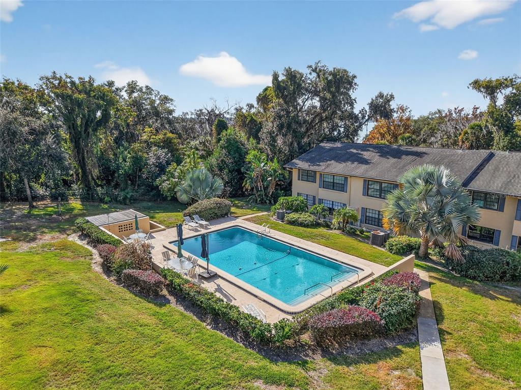 An aerial view shows a rectangular swimming pool surrounded by a patio, landscaping, and trees — 110 N TREMAIN ST UNIT 105, MOUNT DORA, FL