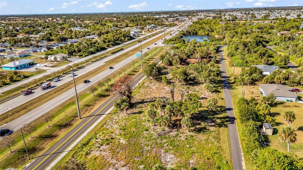 An aerial view shows a vacant lot situated between a highway and a paved path — 3278-3294 N ACCESS ROAD, ENGLEWOOD, FL