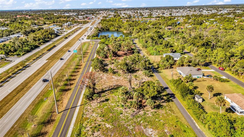 An aerial view shows a vacant lot bordered by a highway and a residential street — 3278-3294 N ACCESS ROAD, ENGLEWOOD, FL