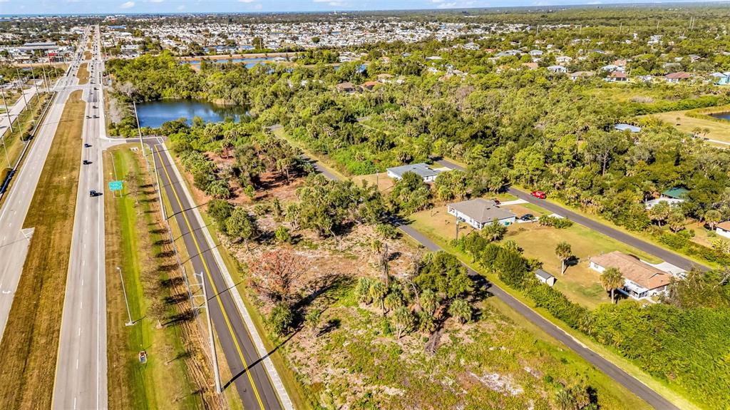An aerial view shows a multi-lane highway running alongside a vacant lot and residential houses — 3278-3294 N ACCESS ROAD, ENGLEWOOD, FL