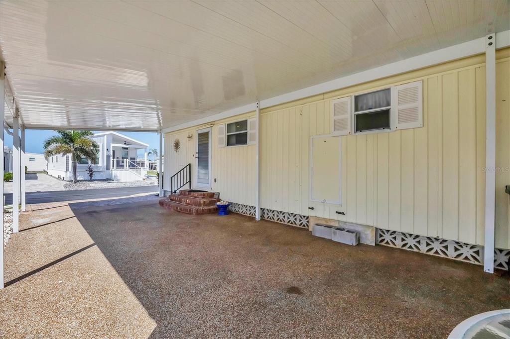 A covered carport sits beside a light yellow mobile home with a small brick staircase — 14 S FLORA VISTA STREET, ENGLEWOOD, FL