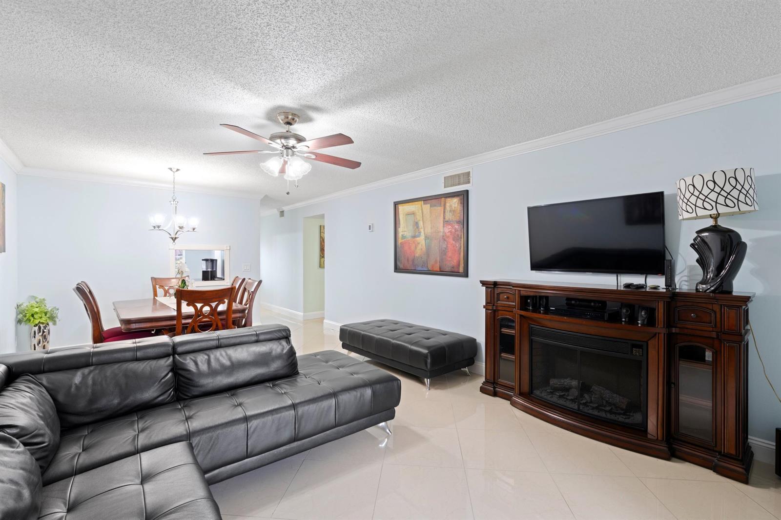 A living room features a black leather sectional, a fireplace media console, and a dining area — 300 NE 26th Avenue # 1030, Boynton Beach FL 33435, BOYNTON BEACH, FL