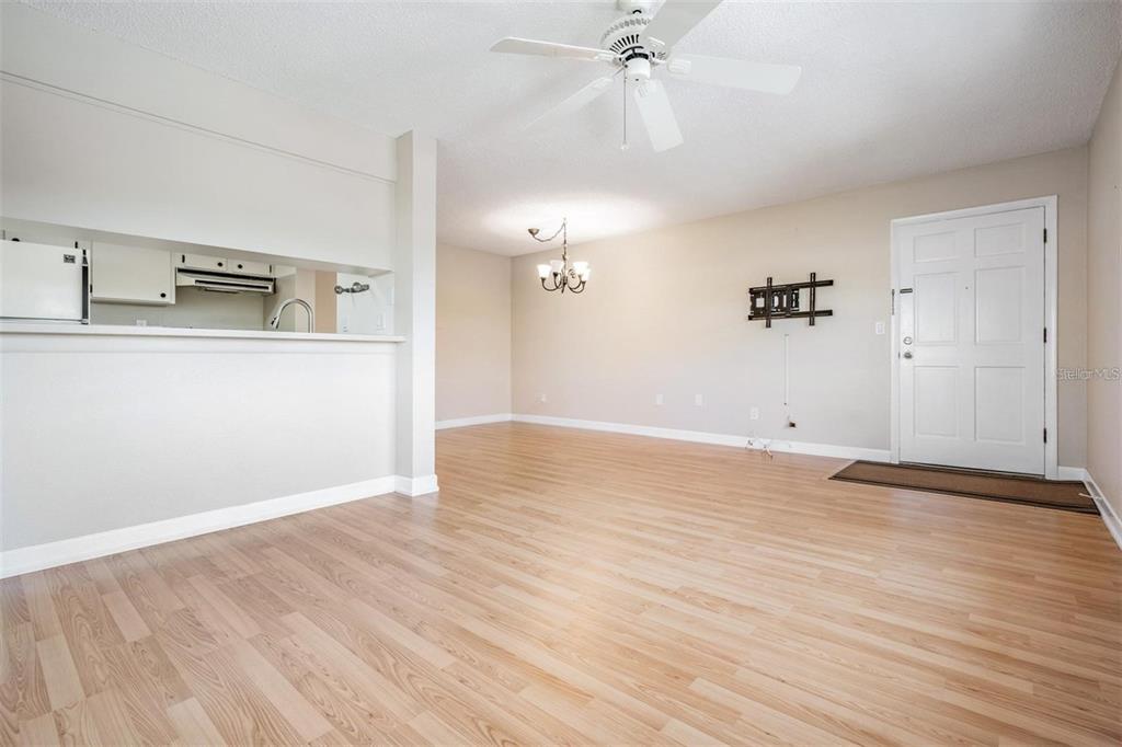 An open-concept living and dining area features light wood-look flooring and a ceiling fan — 2525 WEST BAY DRIVE UNIT B44, BELLEAIR BLUFFS, FL