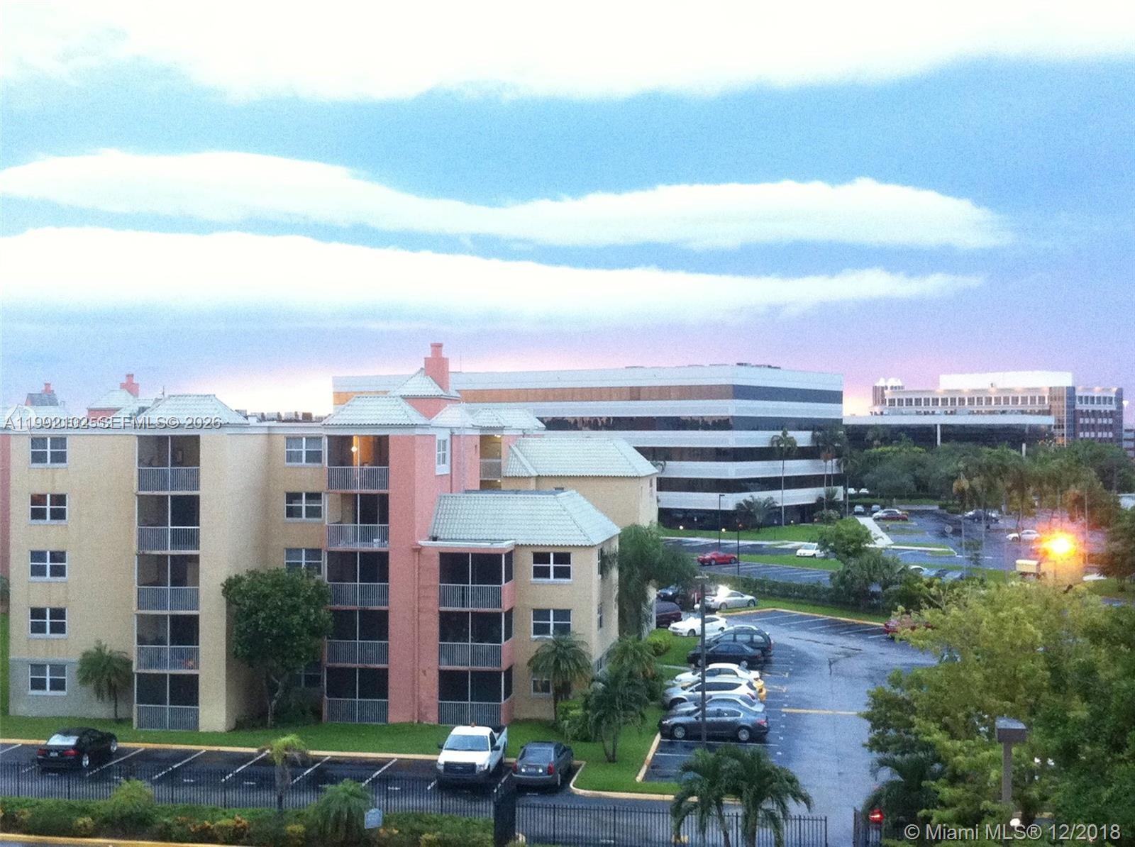 An exterior view of a multi-story apartment building with a parking lot at dusk — 8100 Geneva Ct # 432, Doral FL 33166, DORAL, FL