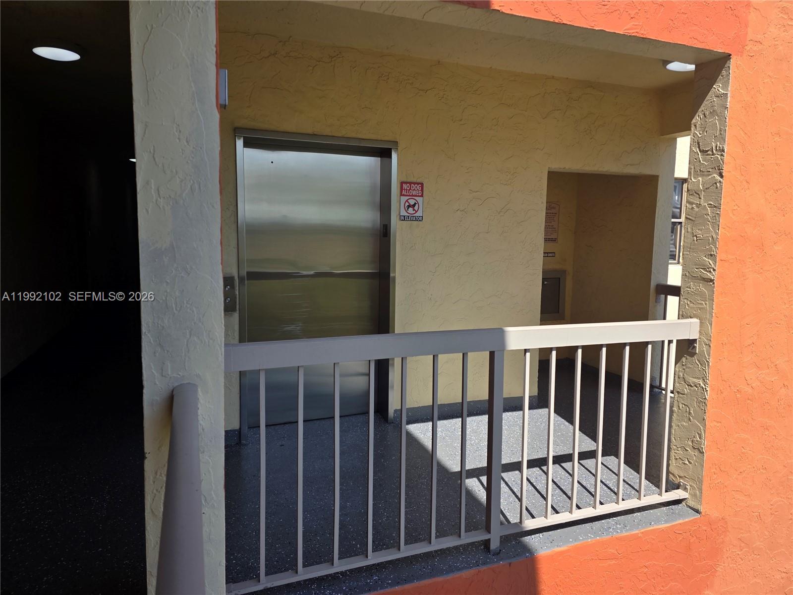 An outdoor elevator landing features a metal door, a railing, and a trash chute — 8100 Geneva Ct # 432, Doral FL 33166, DORAL, FL