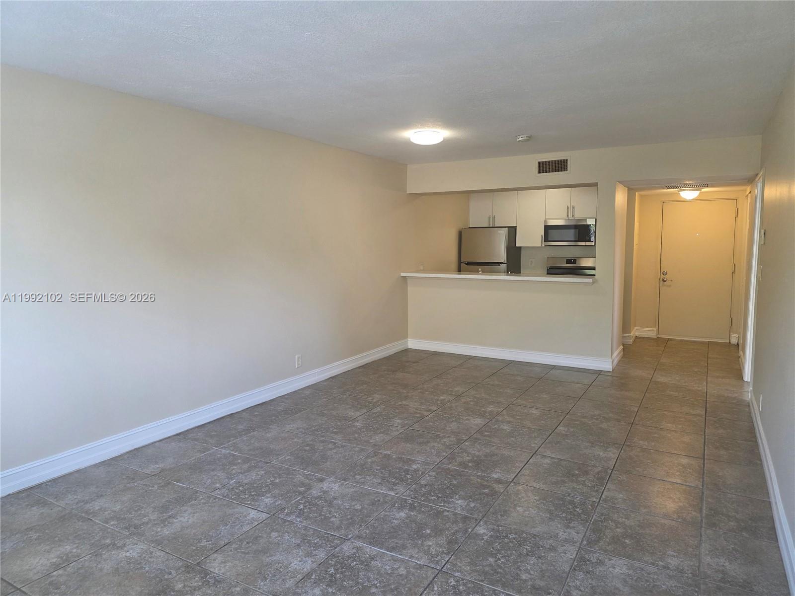 An open-concept living area features beige walls, tile flooring, and a kitchen with white cabinets — 8100 Geneva Ct # 432, Doral FL 33166, DORAL, FL