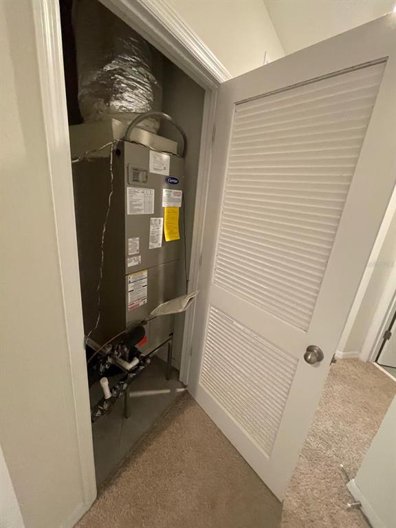 A utility closet contains a Carrier HVAC unit with exposed ductwork and plumbing — 12411 BOWES BRANCH ROAD, ORLANDO, FL