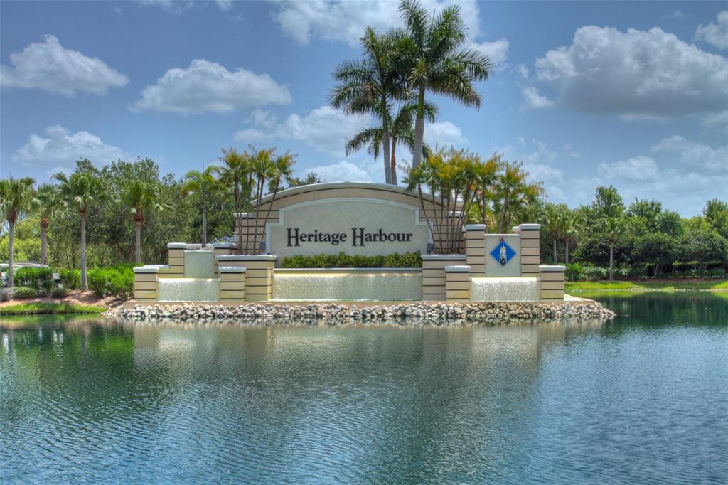 A stone monument sign for Heritage Harbour sits in front of a pond with fountains — 905 FAIRWAY COVE LANE UNIT 205, BRADENTON, FL
