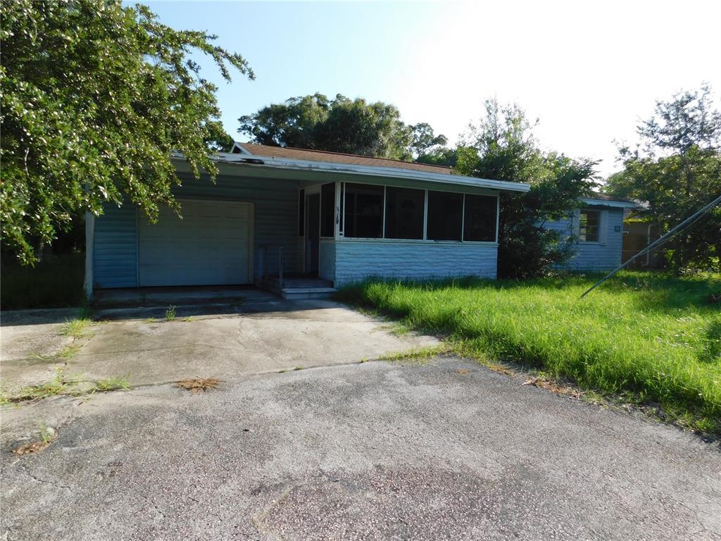 A single-story house with a garage, screened porch, and overgrown lawn under a clear sky — 510 6TH AVENUE NW, LARGO, FL