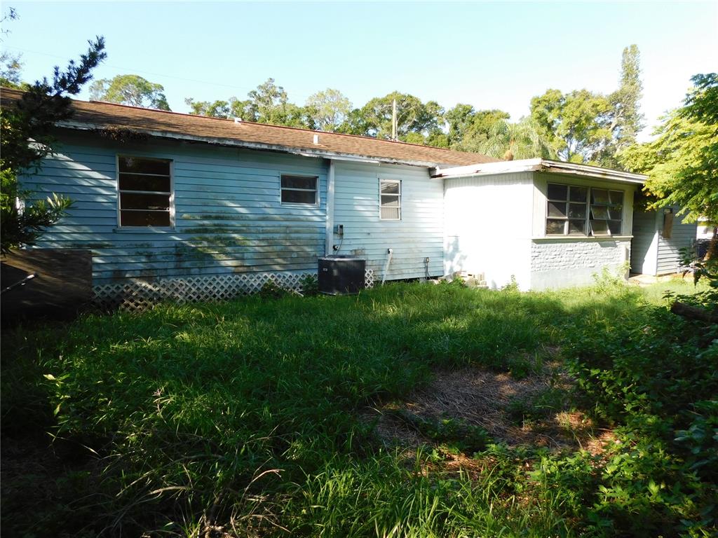 The exterior of a single-story house with light blue siding and an overgrown lawn — 510 6TH AVENUE NW, LARGO, FL