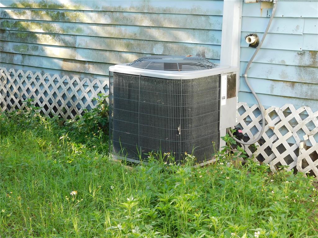 An outdoor air conditioning unit sits on the grass next to a house with siding — 510 6TH AVENUE NW, LARGO, FL