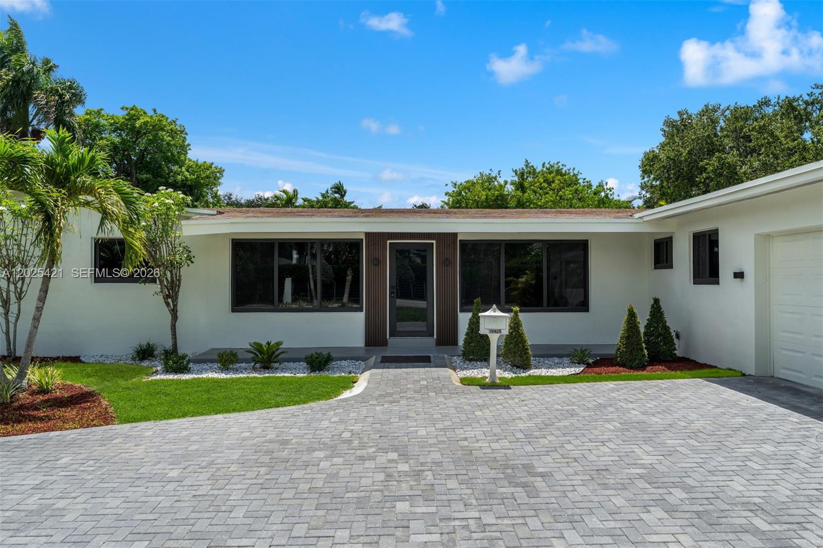 A single-story house with a white exterior, dark-framed windows, and a paved driveway — 10825 SW 80th Ave, Miami FL 33156, MIAMI, FL