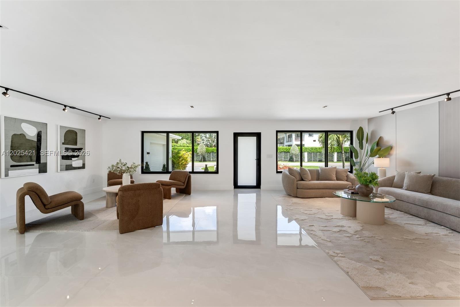 A spacious, minimalist living room features white tile floors, neutral furniture, and large windows — 10825 SW 80th Ave, Miami FL 33156, MIAMI, FL