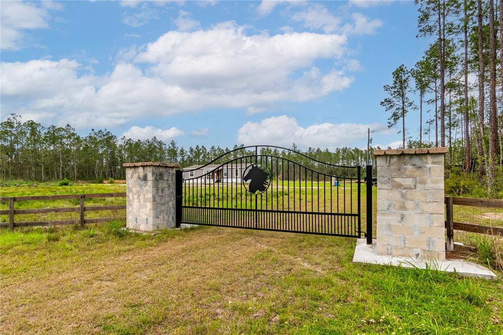 A black metal gate with a horse silhouette stands between two stone pillars — 12655 NE 215TH STREET, FORT MC COY, FL