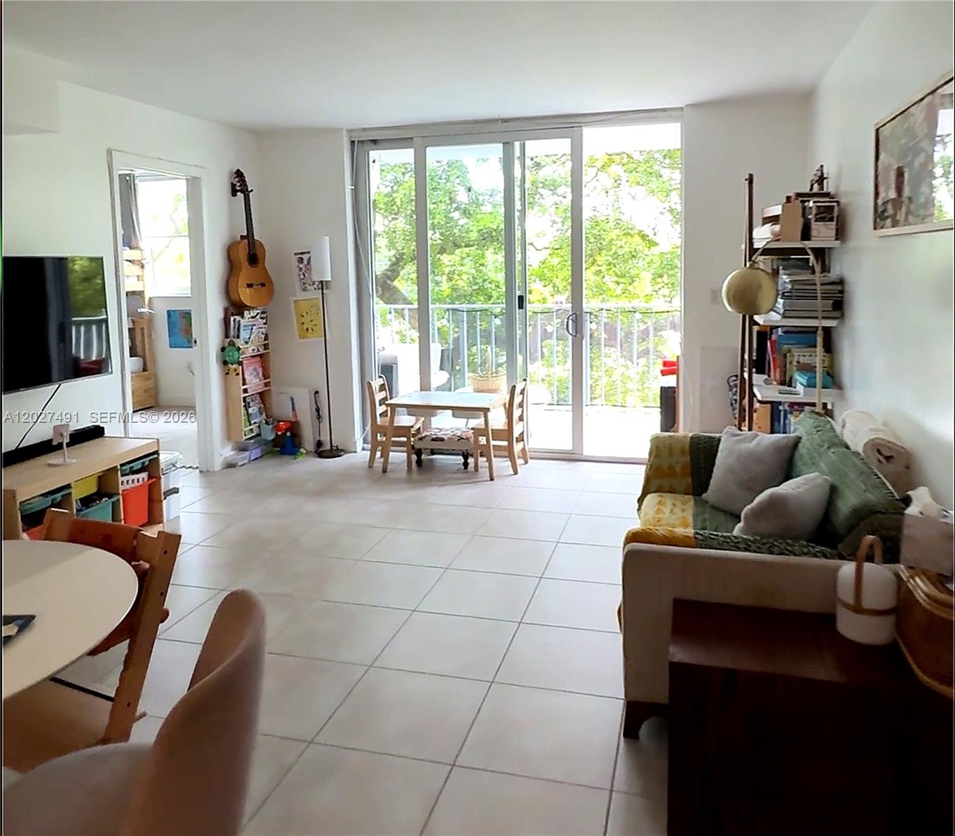 A living room with tile floors, a sofa, a dining area, and a sliding glass door — 650 NE 64th St # G402, Miami FL 33138, MIAMI, FL