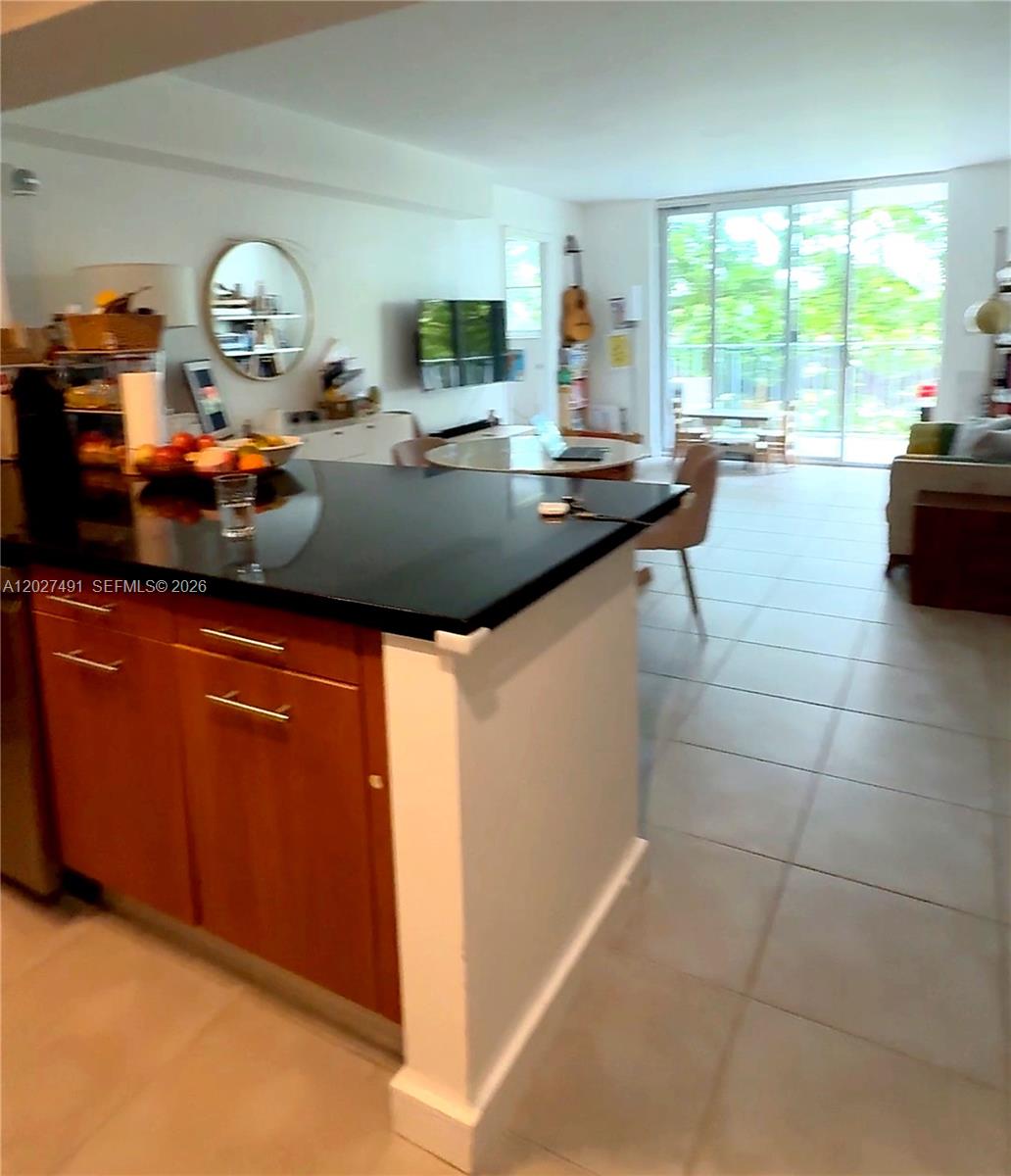 A kitchen island with a black countertop overlooks an open-concept living and dining area — 650 NE 64th St # G402, Miami FL 33138, MIAMI, FL