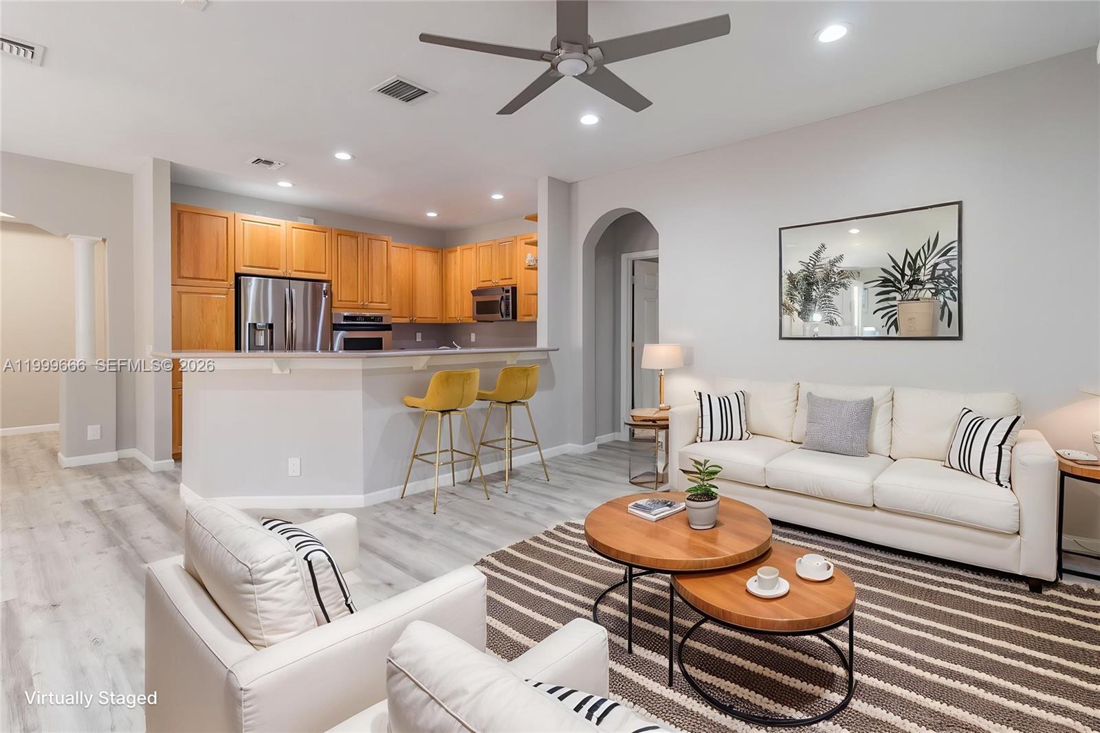 An open-concept living room and kitchen featuring light wood cabinets and white upholstered furniture — 1611 Passion Vine Cir # 2, Weston FL 33326, WESTON, FL