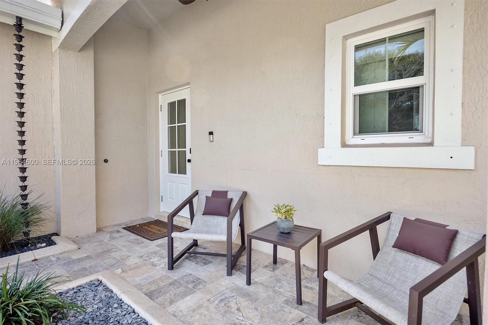 A patio features two chairs, a small table, a white door, and a window — 1602 SE 20th Rd, Homestead FL 33035, HOMESTEAD, FL