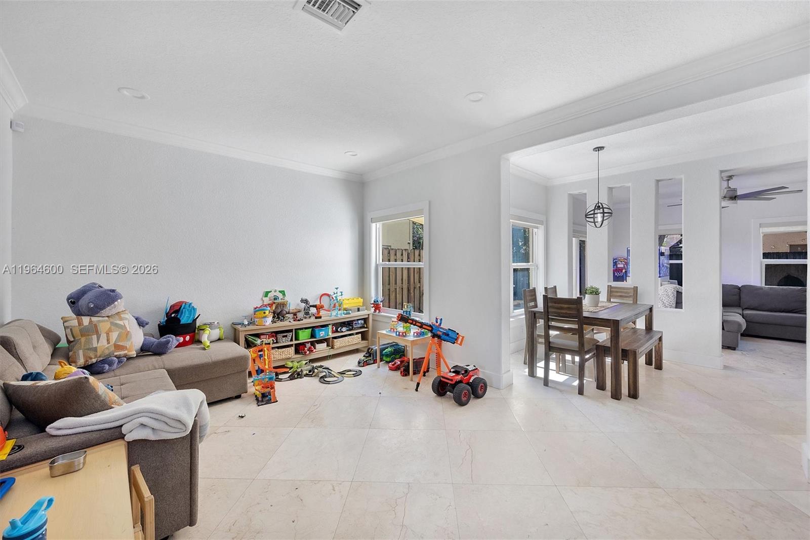A living area with tile floors flows into a dining space with a wooden table — 1602 SE 20th Rd, Homestead FL 33035, HOMESTEAD, FL
