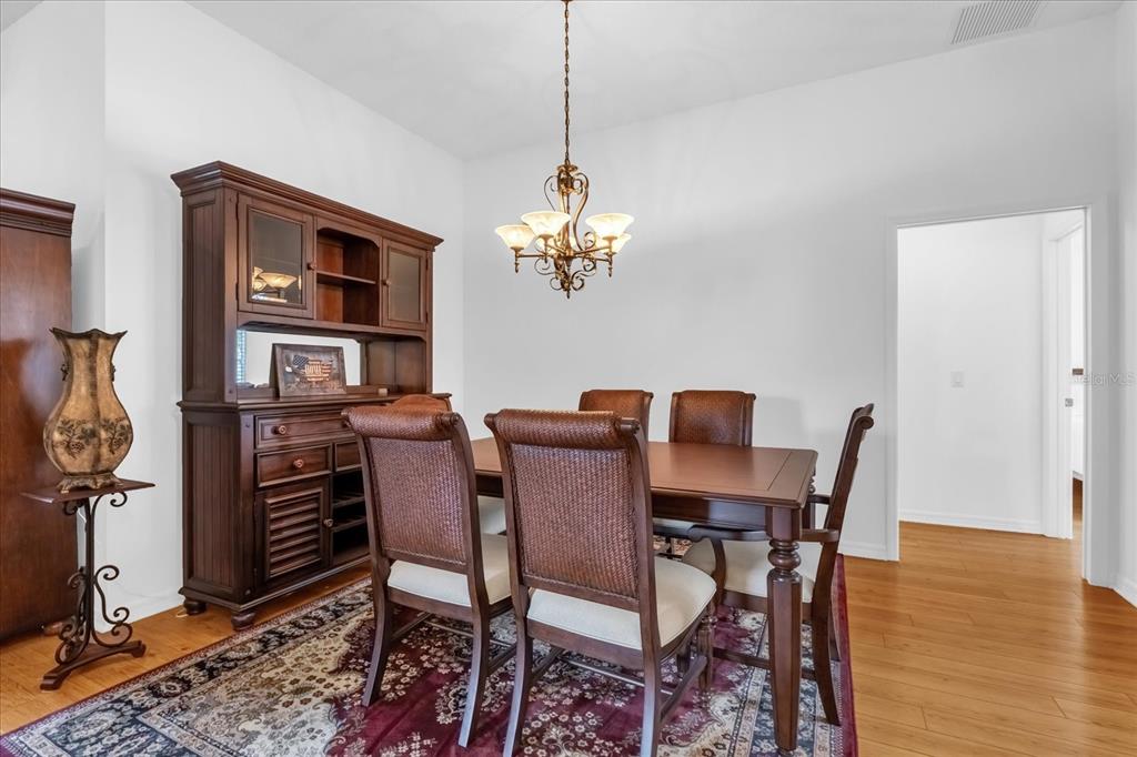 A dining room features a wooden hutch, a table with four chairs, and a chandelier — 1462 PELICAN PATH, THE VILLAGES, FL